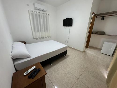 a small room with a bed and a tv at Suítes Betel in Paraty