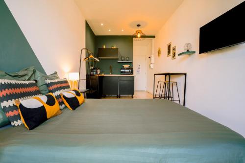 a bedroom with a large green bed with pillows at Le studio tendance in Albi