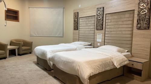 a bedroom with two beds and a chair and a window at فندق دلسDELS HoTEL in Tabuk