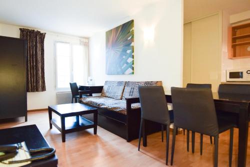 uma sala de estar com um sofá e uma mesa em Residhotel Mulhouse Centre em Mulhouse