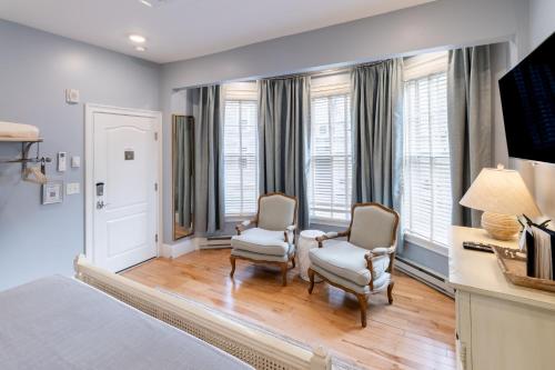 a bedroom with two chairs and a bed and windows at The Outlook Inn in Newport