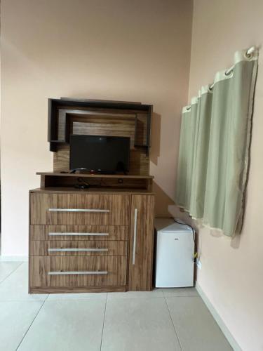a television on a wooden cabinet in a room at Suítes Betel in Paraty