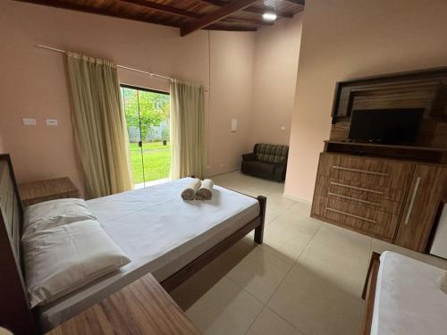a bedroom with a bed and a large window at Suítes Betel in Paraty