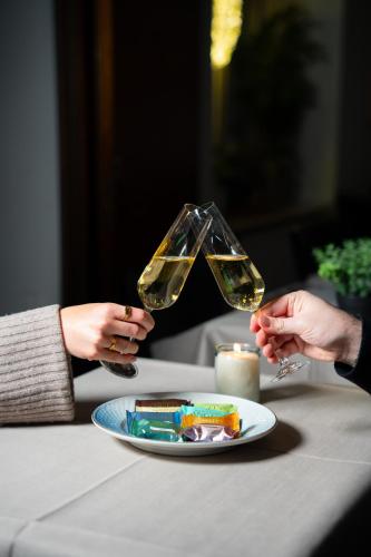 two people holding wine glasses over a plate of food at Palads Hotel in Viborg