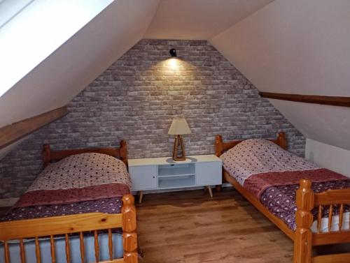 - une chambre mansardée avec 2 lits et un mur en briques dans l'établissement Maison au calme, à Chelles