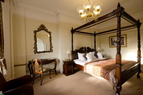 a bedroom with a canopy bed and a desk and a mirror at Hatton Court Hotel in Gloucester