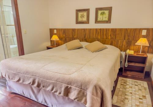 a bedroom with a large bed with two pillows on it at Pousada Victoria Villa By Nacional Inn - A 800 metros da Vila Capivari in Campos do Jordão