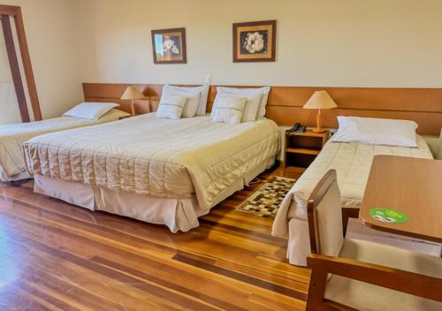 two beds in a room with wooden floors at Pousada Victoria Villa By Nacional Inn - A 800 metros da Vila Capivari in Campos do Jordão