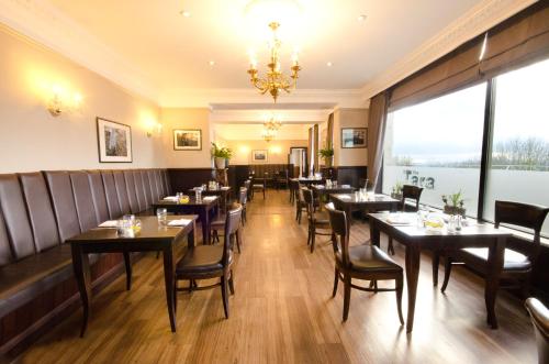 a restaurant with tables and chairs and a large window at Hatton Court Hotel in Gloucester
