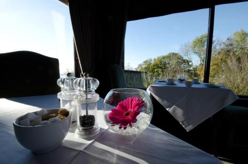 a table with glasses and a flower in a bowl at Hatton Court Hotel in Gloucester