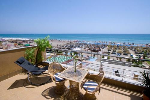 einen Balkon mit einem Tisch und Stühlen sowie einem Strand in der Unterkunft Carihuela Beach Apartamentos in Torremolinos