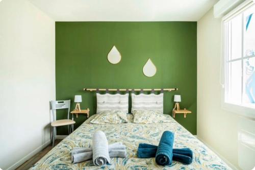 a bedroom with a large bed with a green wall at Les Épinettes in Cayeux-sur-Mer