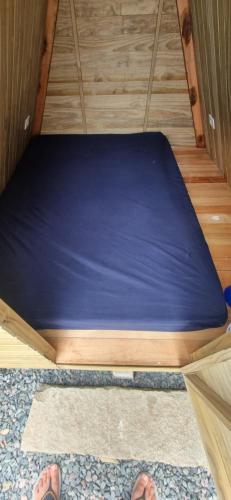 a bed in a room with two feet on the floor at Ecox Hostel Cabanas 2 in Penha