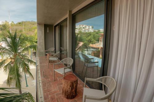 a balcony with chairs and a table and a window at Unnu in Santa Cruz Huatulco
