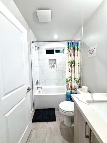 a white bathroom with a toilet and a bath tub at Newly built home, ample parking, near SEA Airport in Tukwila