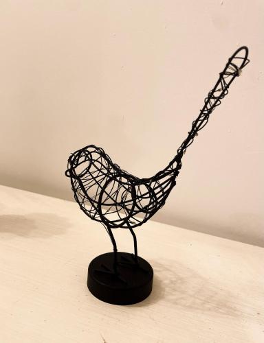 a black wire bird sculpture on a black base at Biffi 2 - Garbatella Rooms in Rome
