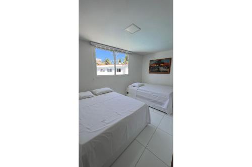 a bedroom with two beds and a window at Flats no Mandakaru Residence (Flats da Elena) in Porto De Galinhas