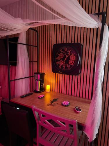 une chambre avec une table et une horloge sur le mur dans l'établissement Love room nantais, à Nantes