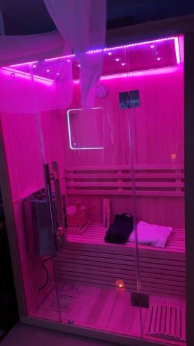 une chambre avec des lumières roses dans une chambre avec un lit dans l'établissement Love room nantais, à Nantes
