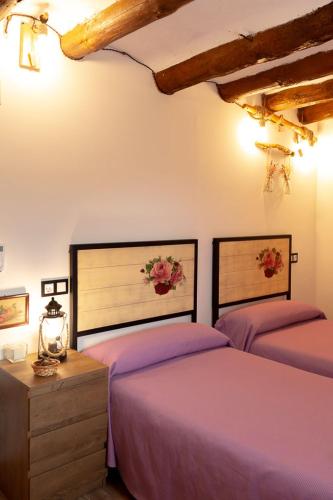 two beds in a room with purple sheets at Casa rural Bisimbre in Bisimbre