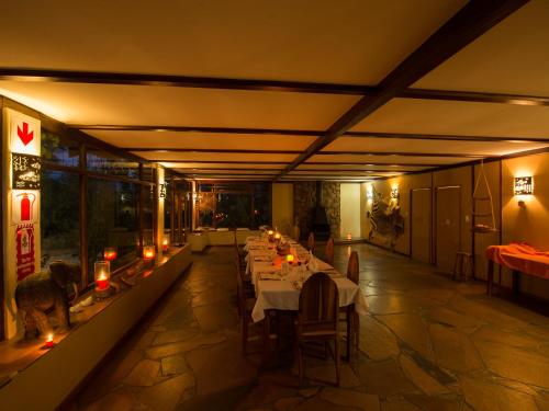 a long dining room with long tables and candles at Halala Africa Lodge - Eagle Rock Lodge in Malabar