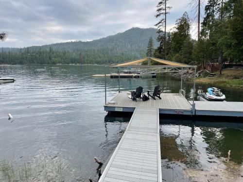 a dock with two chairs and a boat on a lake at Werner Lake Front in Bass Lake