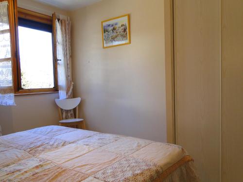 a bedroom with a bed and a window and a chair at Gîte 829 Montagnes du Jura avec Spa et Sauna classé 3 étoiles in Foncine-le-Haut