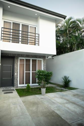 a white house with a black door and a porch at Townhouse - Centrico - Modern - 3 hab - Patio in San Pedro Sula