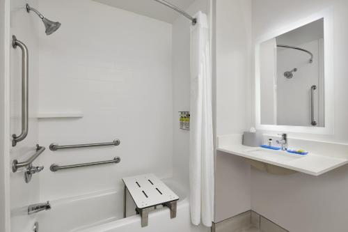 a white bathroom with a tub and a sink at Holiday Inn Express Hotel & Suites Pensacola-West Navy Base by IHG in Pensacola