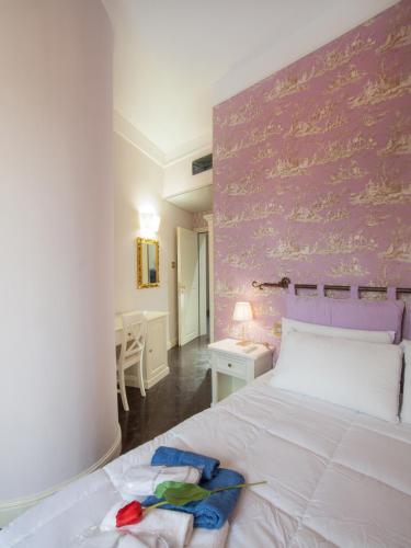 a bedroom with a white bed with a pink wall at Il Duomo Relais in Ragusa