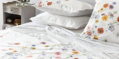 - un lit avec une couette et des oreillers blancs dans l'établissement Le petit Studio, à Saint-Nazaire