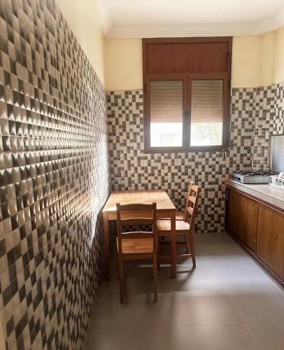 a table and chairs in a kitchen with tiles on the wall at residence rose des sables in Dakhla