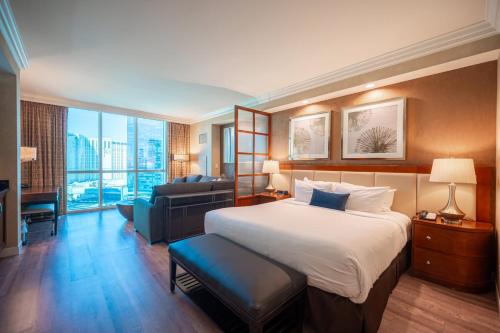 a hotel room with a bed and a couch at No Resort Fee Strip View Suite + Free Valet + Pool in Las Vegas