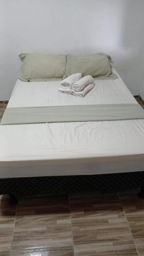 a bed with two towels sitting on top of it at Chácara Acolhedora! in Majé