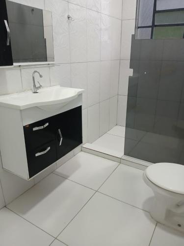 a white bathroom with a sink and a shower at Chácara Acolhedora! in Majé
