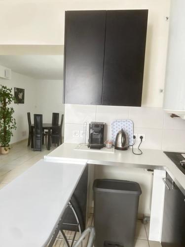 une cuisine avec des comptoirs blancs et des armoires noires dans l'établissement Tal's Duplax, à Villeurbanne