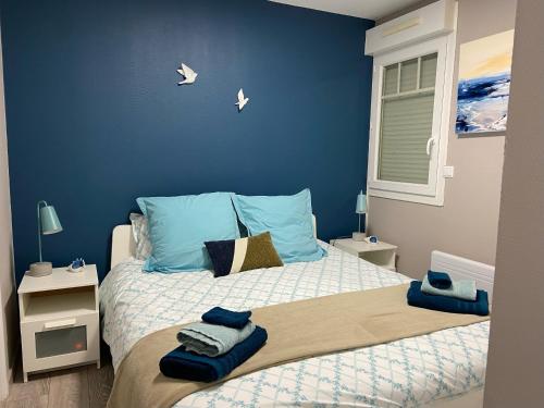 - une chambre avec des murs bleus et un lit avec des serviettes dans l'établissement LE BON ENDROIT en bord de mer, vue mer , parking et wifi, à Wimereux