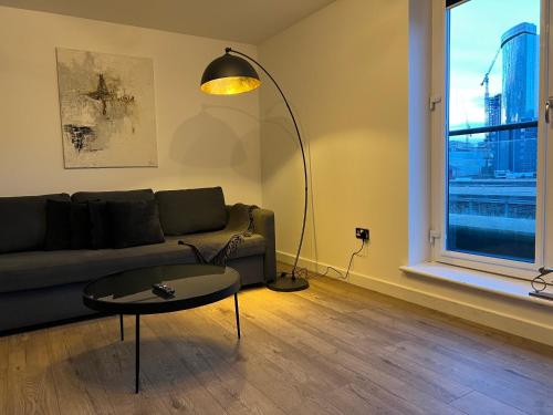 a living room with a couch and a table and a lamp at 2 Bedroom Penthouse City View in Birmingham