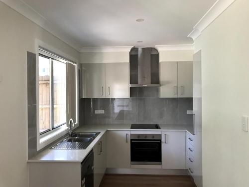 a kitchen with white cabinets and a sink and a window at New stand-alone 2-bedroom house in Baulkham Hills
