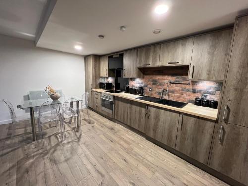 a kitchen with wooden cabinets and a table in it at 2 Bedroom Penthouse City View in Birmingham