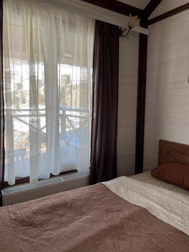 a bedroom with a bed and a window with curtains at Готельно-Ресторанний комплекс Кичера in Volovets