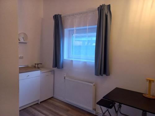 a kitchen with a window with blue curtains and a table at Сјајни лешник in Zrenjanin