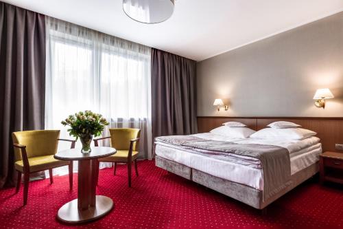 a hotel room with a bed and a table and chairs at Hotel Konradówka Wellness & SPA - 300 metrów do centrum in Karpacz