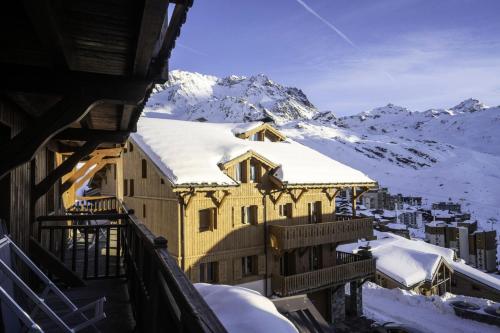 un bâtiment recouvert de neige avec une montagne en arrière-plan dans l'établissement Chalet Mouflon - 4 Pièces pour 6 Personnes MAE-1791, à Val Thorens