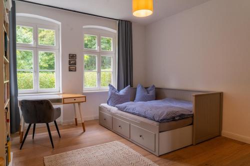 a bedroom with a bed and a desk and windows at Wald- und Seeidyll im historischen Forsthaus in Neuruppin