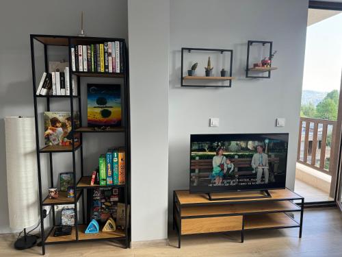 a living room with a flat screen tv and shelves at Хубавото място - Ski & Relax next to Pamporovo in Smolyan