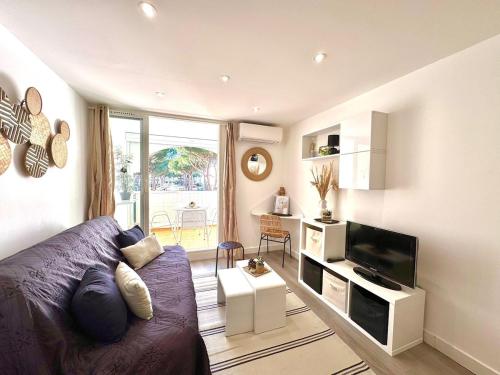 un salon avec un canapé et une télévision dans l'établissement Le Grand Bleu-Parking privé-Climatisation-Proche ponant, à La Grande Motte