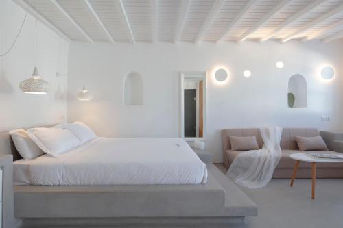 a white bedroom with a bed and a couch at Beyond Blue Suite in Mýkonos City