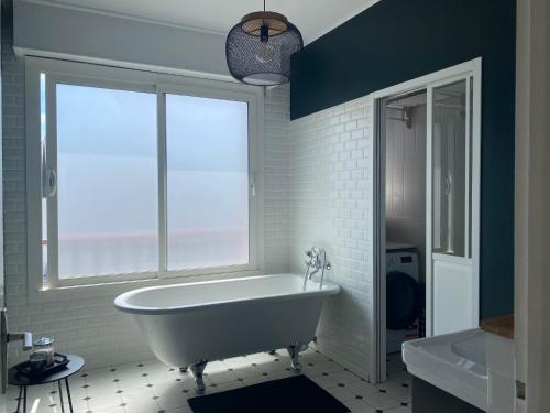 La salle de bains blanche est pourvue d'une baignoire et d'une fenêtre. dans l'établissement Bel appartement centre-ville, à Lorient
