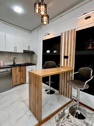 a kitchen with a wooden counter and two bar stools at Holiday Home in Baku
